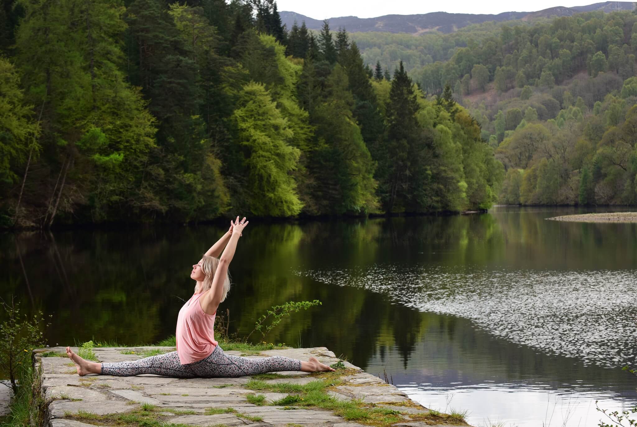 Een persoon die yoga doet op een rots in de buurt van water