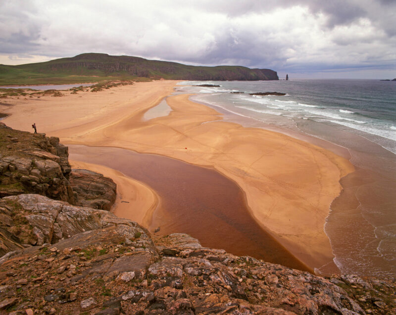 A Lone Walker Takes In The View Over Sandwood Bay With A View Beyond To The Sea